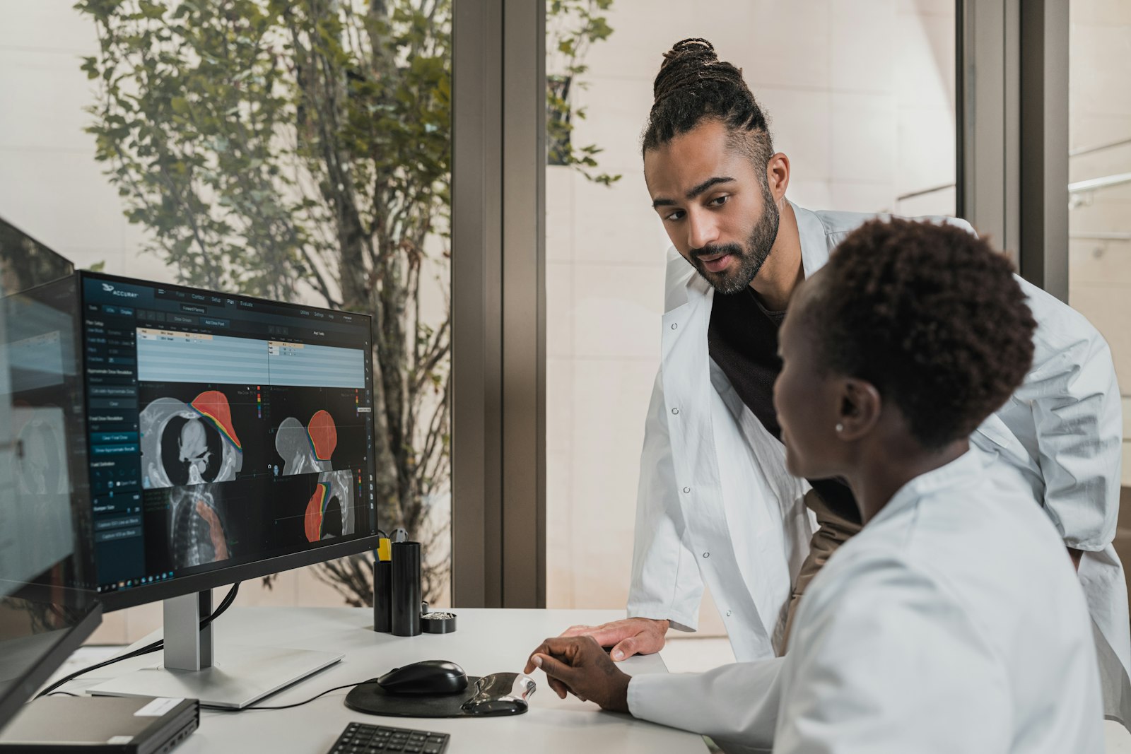 Two clinicians reviewing a treatment plan together on screen — human judgment stays in the loop